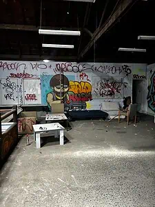 Graffiti-covered abandoned room with scattered furniture, popular in urban exploration and lost place map adventures.